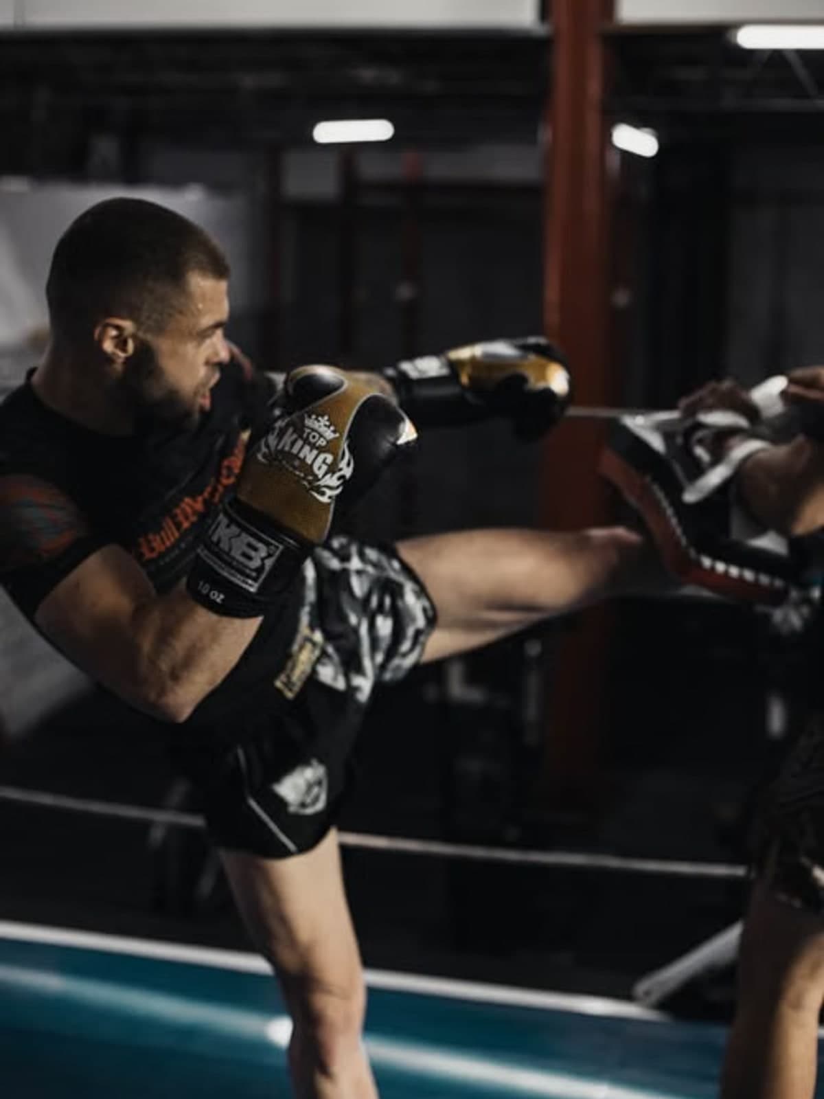 Fighter throwing a high kick to pads in the gym